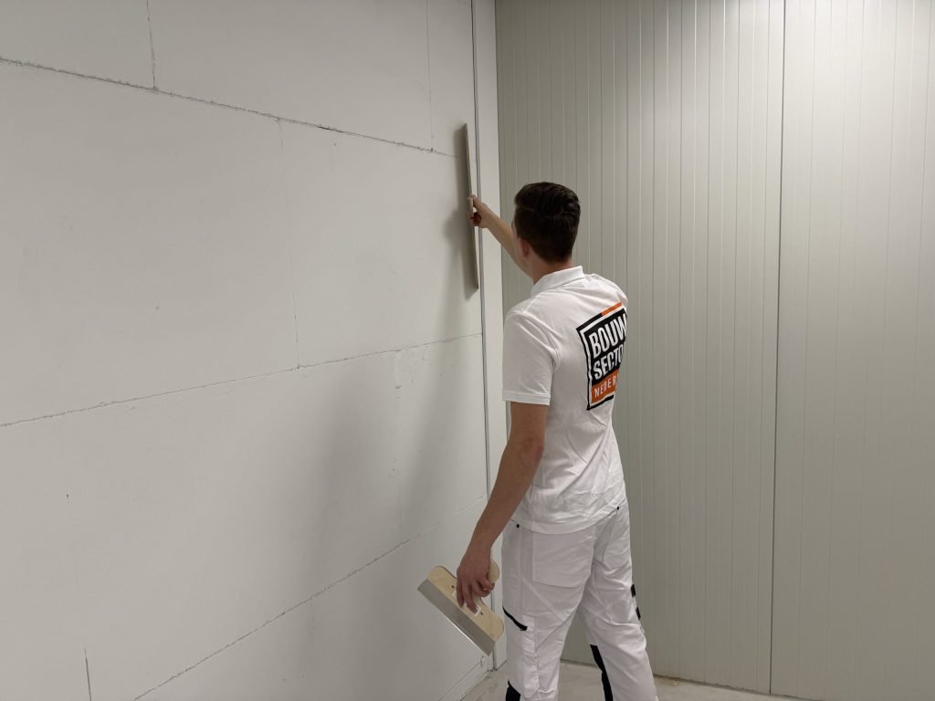 Stukadoor werkt een lange wand van boven naar beneden sausklaar af