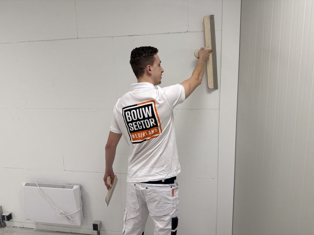 Stukadoor van Bouwsector Nederland zet met een lange spaan een wand vlak